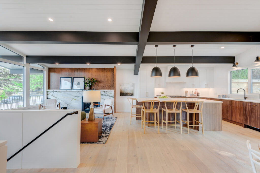 dark wood beams across this open floor plan showing a kitchen with island and living room