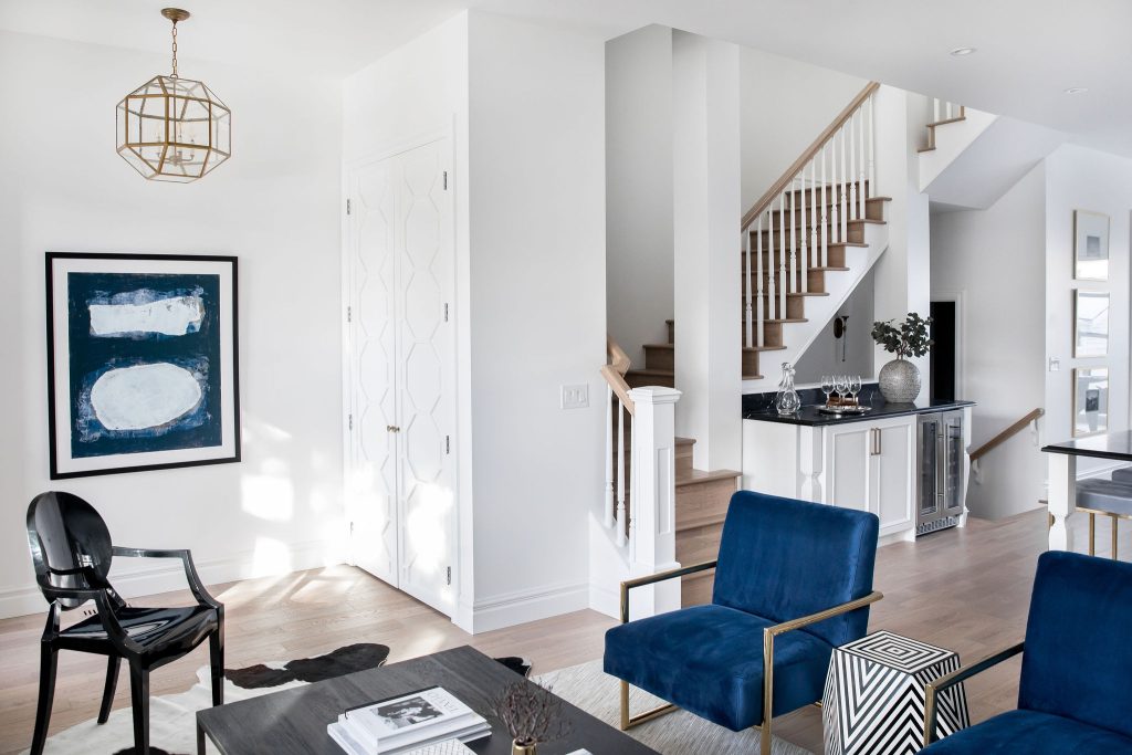 A modern home with white walls, a light hardwood and royal blue chairs.