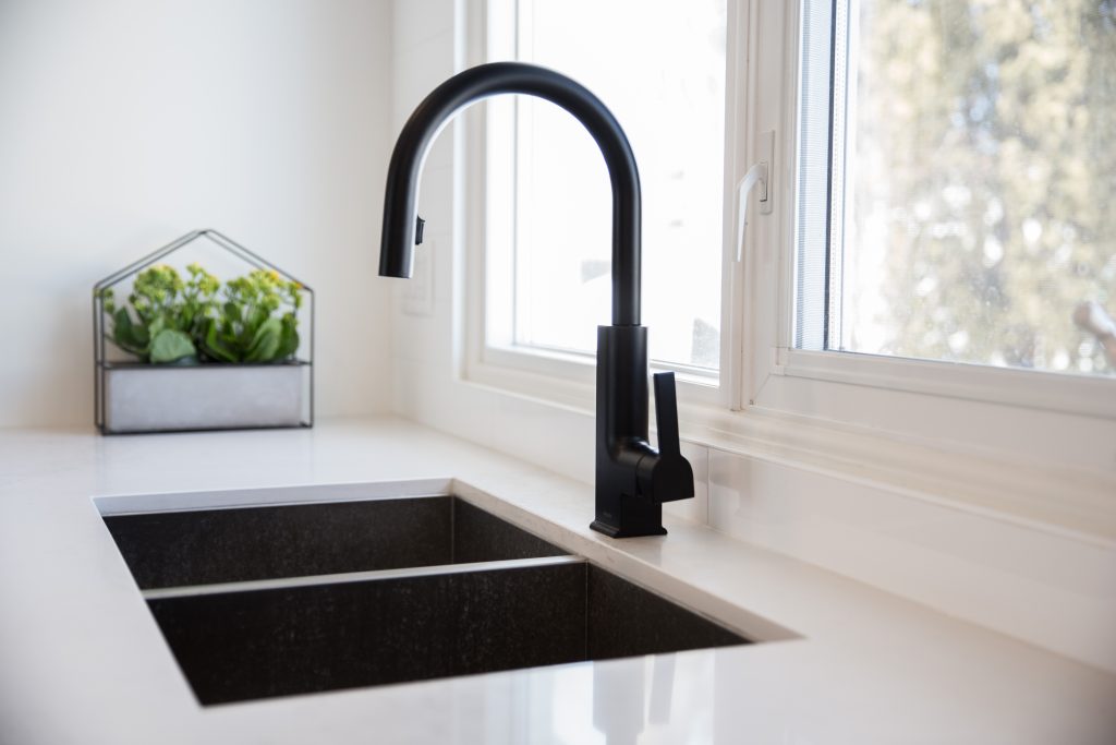 A modern white marble kitchen counter with a square black kitchen sink and black faucet.