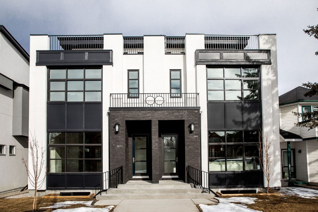 Large modern home with brick, large windows, and multiple balconies