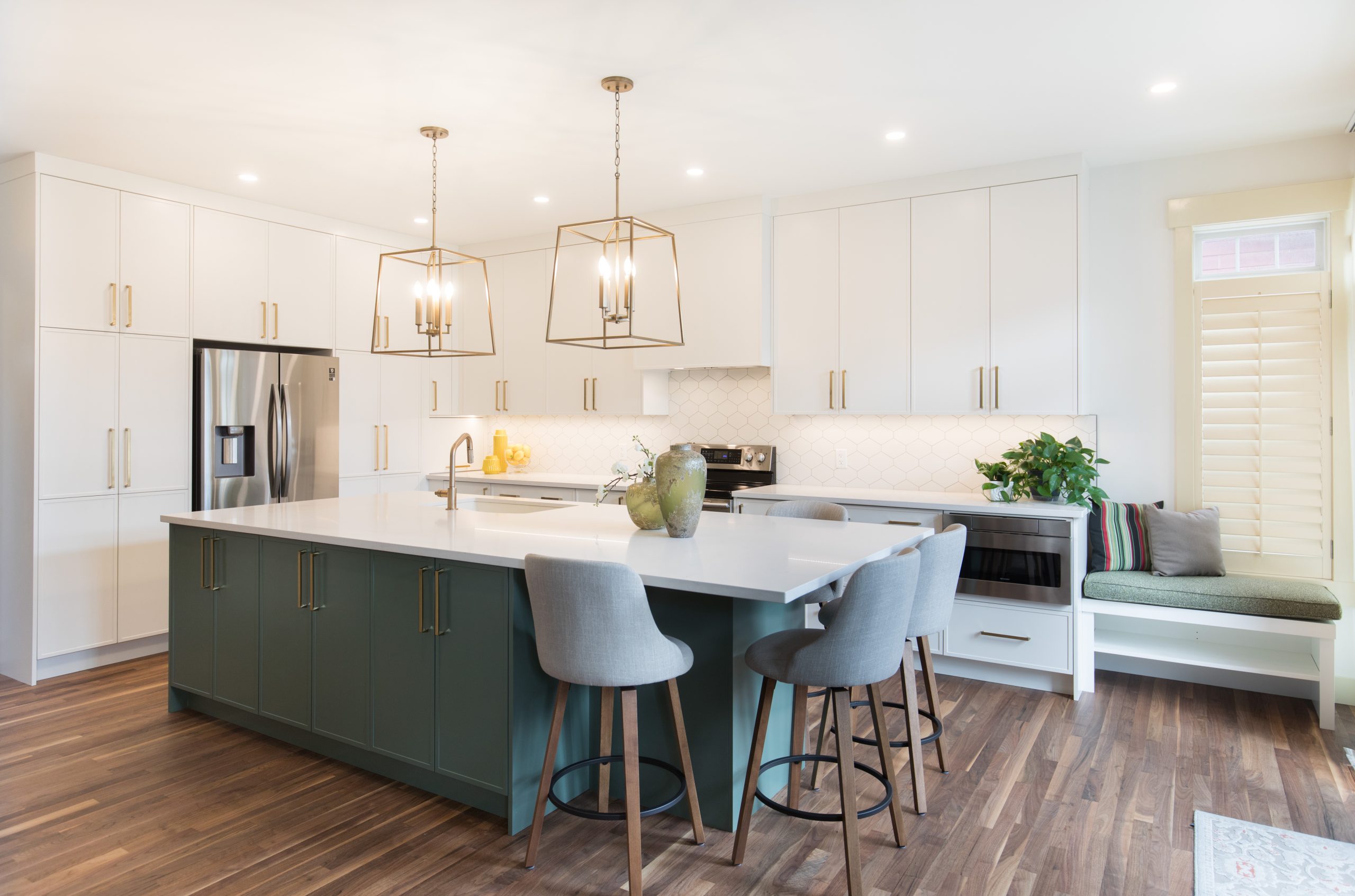Beautiful white and green kitchen with kitchen island, bar seating, and gold pendant lights and hardware