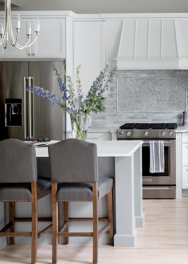 A newly renovated designer kitchen with white cabinets and a white chandelier.