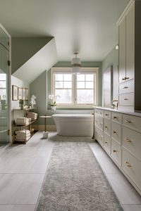 Newly renovated designer bathroom with light green walls, cream cabinets and copper hardware.