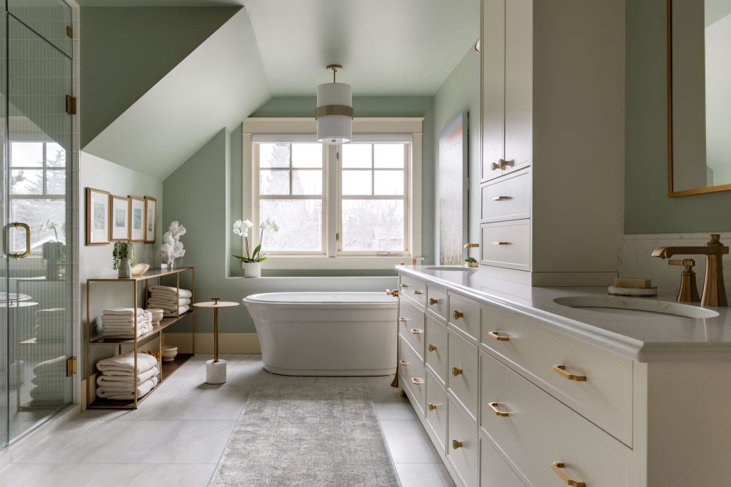 Newly renovated designer bathroom with light green walls, cream cabinets and copper hardware.