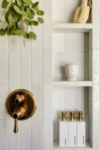 Stunning built in shower niche with brass hardware and natural plants