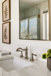 Natural stone bathroom vanity with chrome faucet, rectangular gold framed mirror and bathroom decor