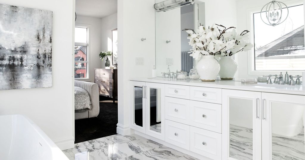 A bathroom with white cabinets and a grey and white marble floor.