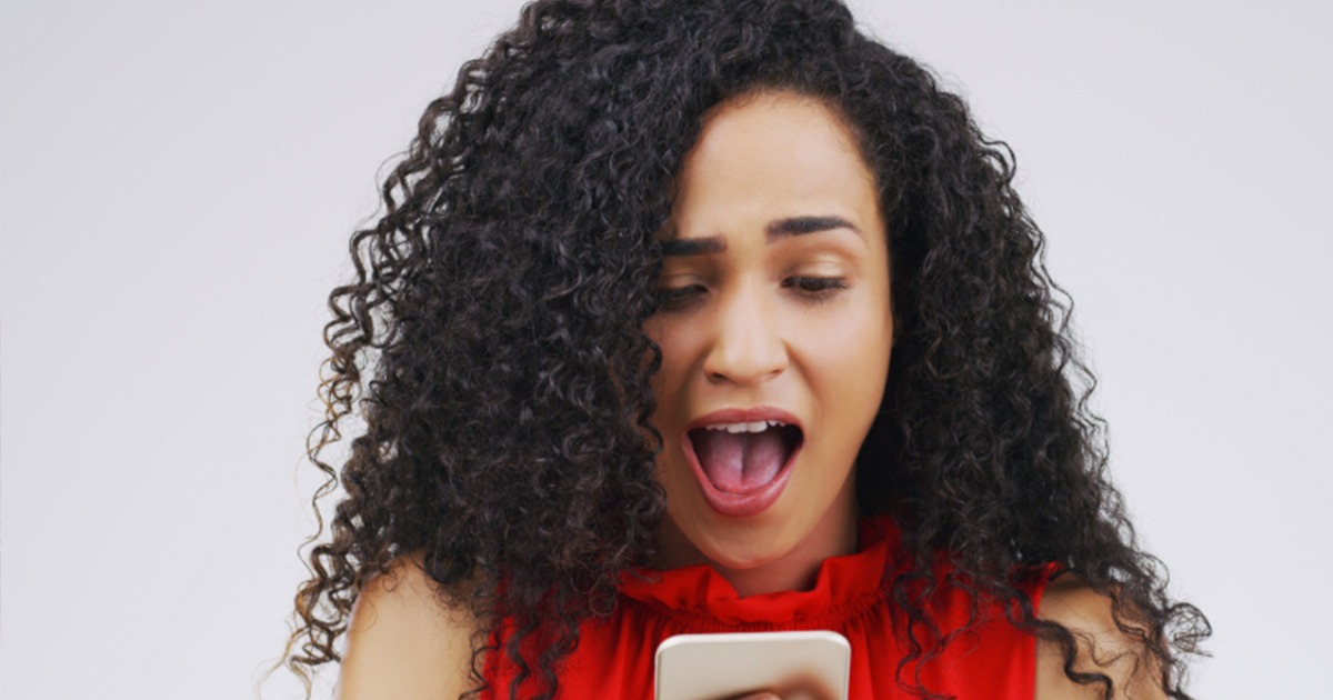 A young woman excited about what she sees on her cell phone.