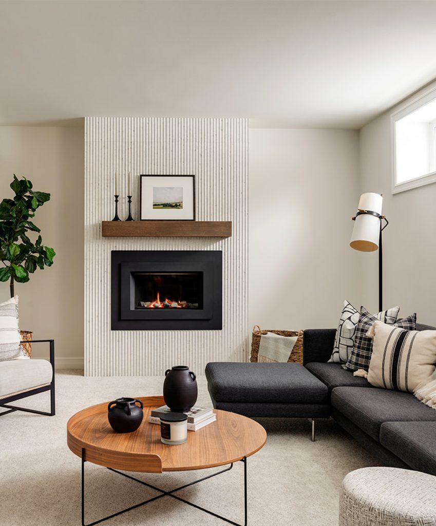 A basement renovated with a fireplace with fluted panels.