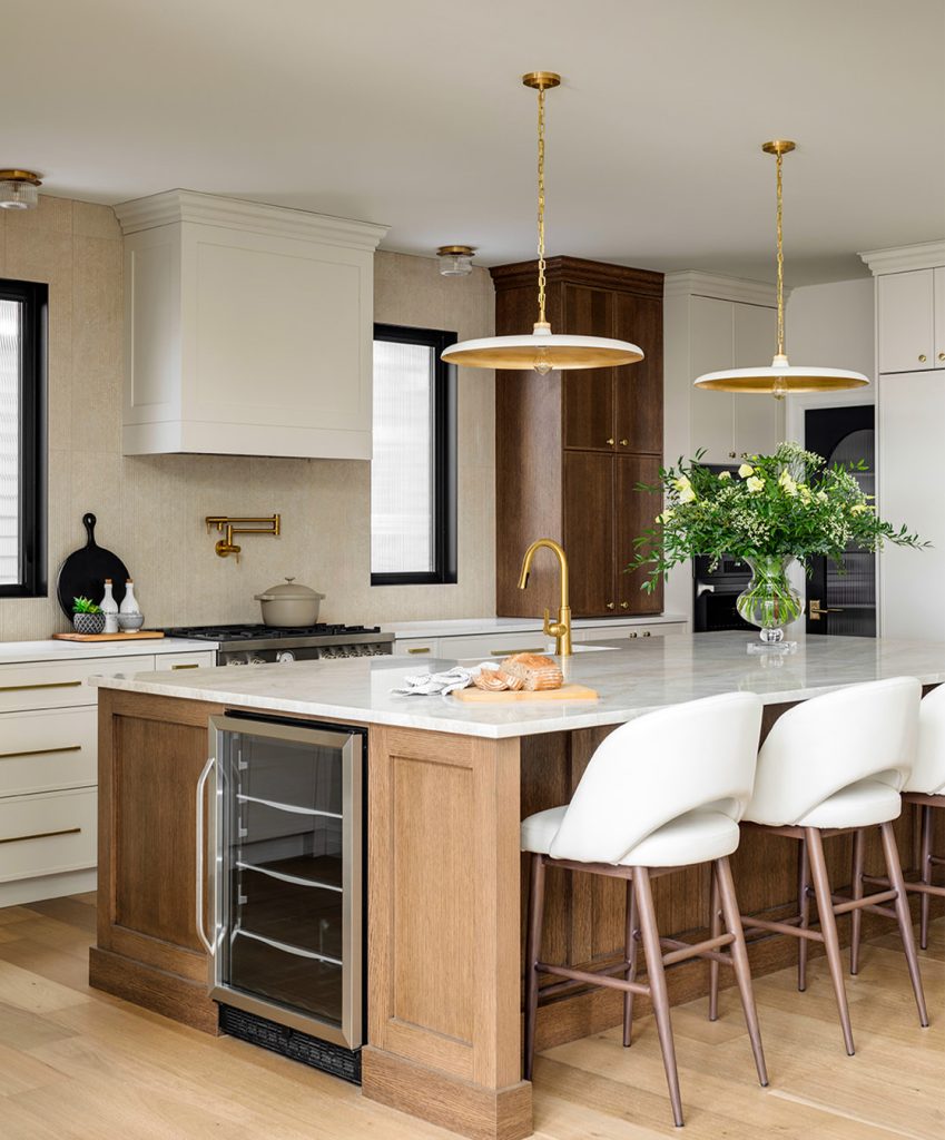 A newly renovated two-tone kitchen with a large island and modern white chairs.