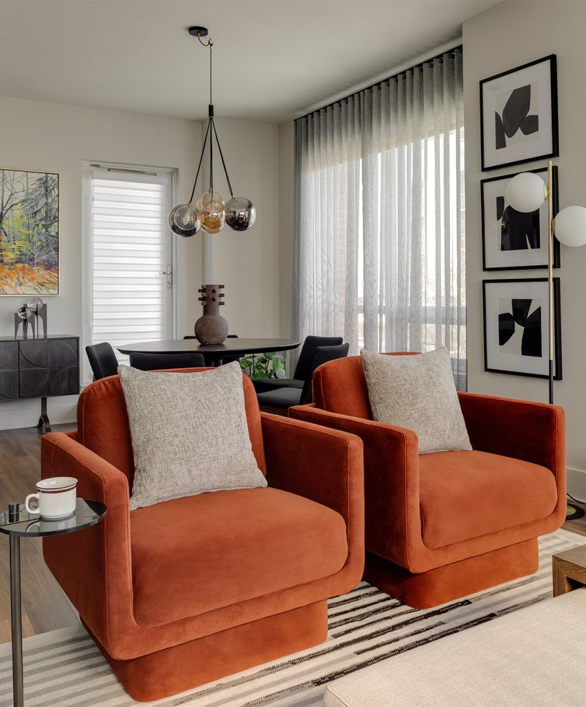 A modern living room featuring square velour orange chairs.