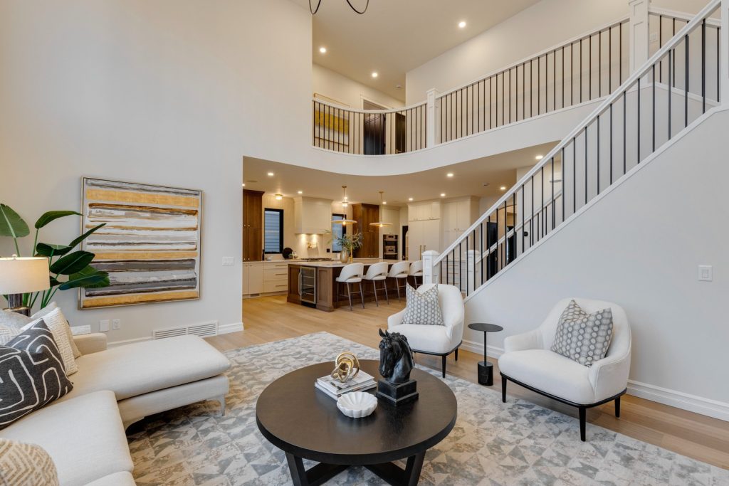 A large double height living room with a long staircase and view into the kitchen.