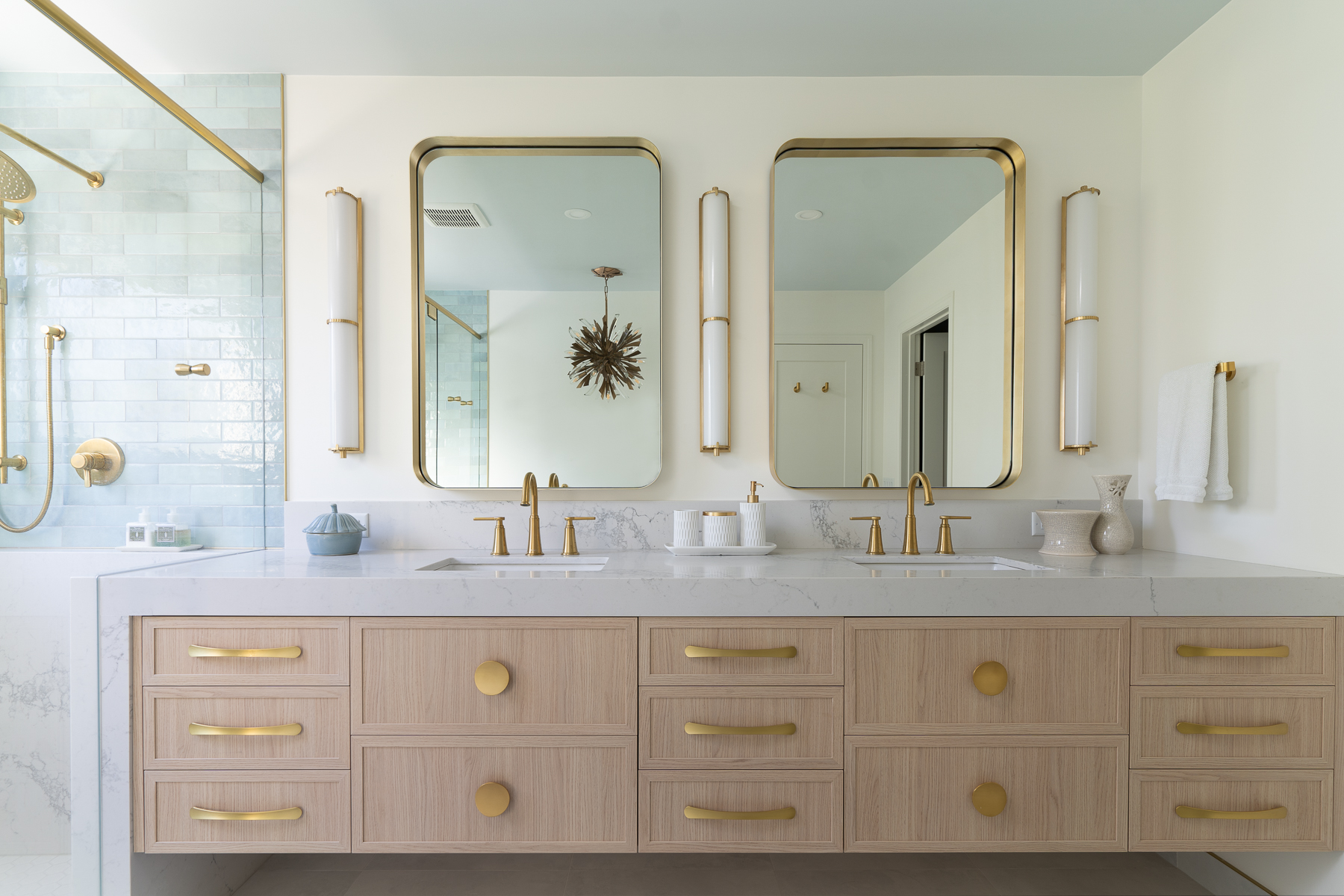 A designer bathroom with maple cabinets and gold fixtures.