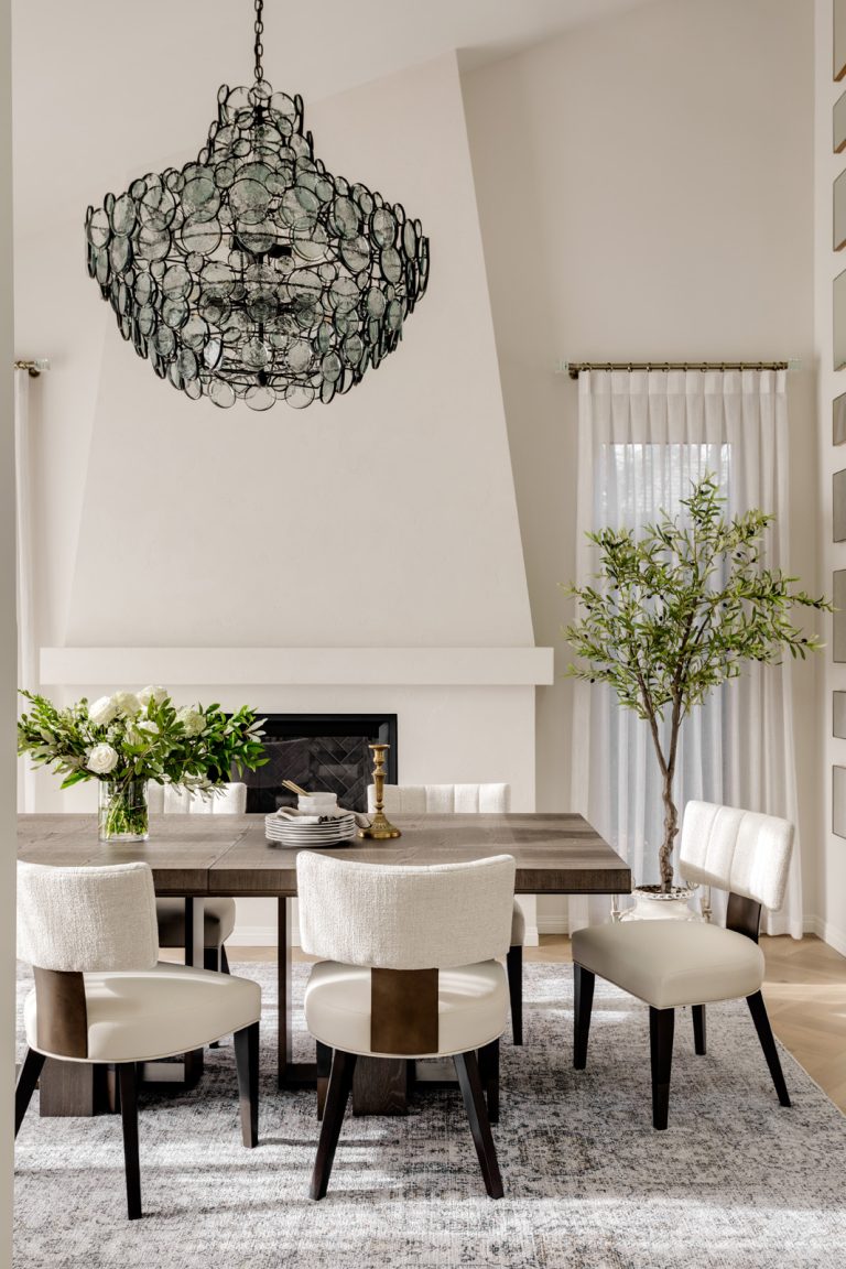 A modern off white dining room with a tall modern Mediterranean-inspired plaster fireplace.