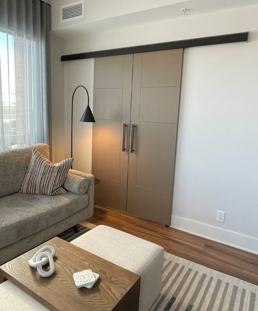 Light brown barn door separating a living room and an office.