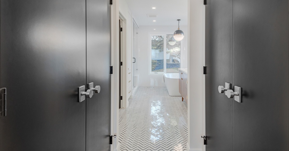 A modern hallway with dark brown close doors leading into a white bathroom.